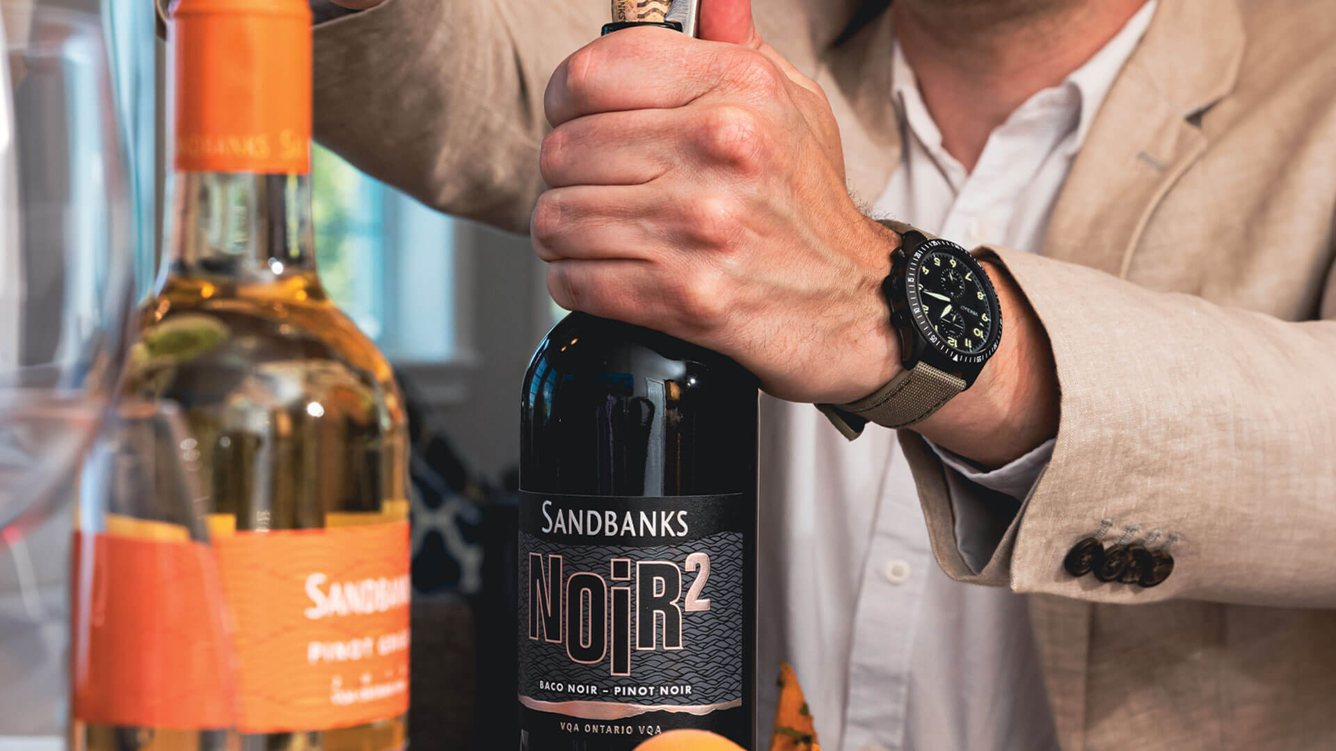 Wine enthusiast uncorking a bottle of Sandbanks Noir 2 and pairing it with some fresh fruit and berries. 