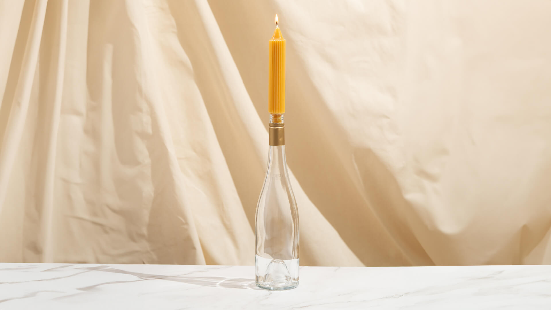 An empty Saintly wine bottle being used as a candle holder.