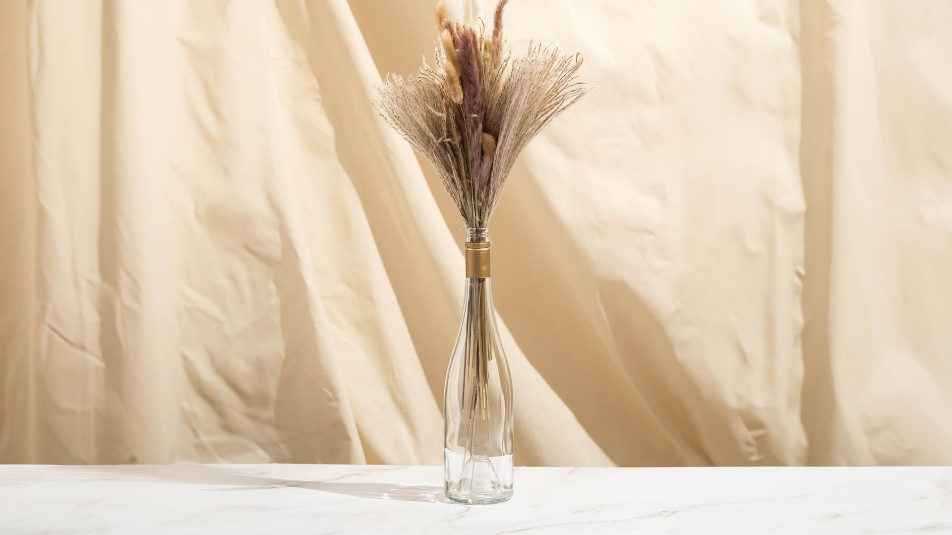 An empty Saintly wine bottle being used as a flower vase.