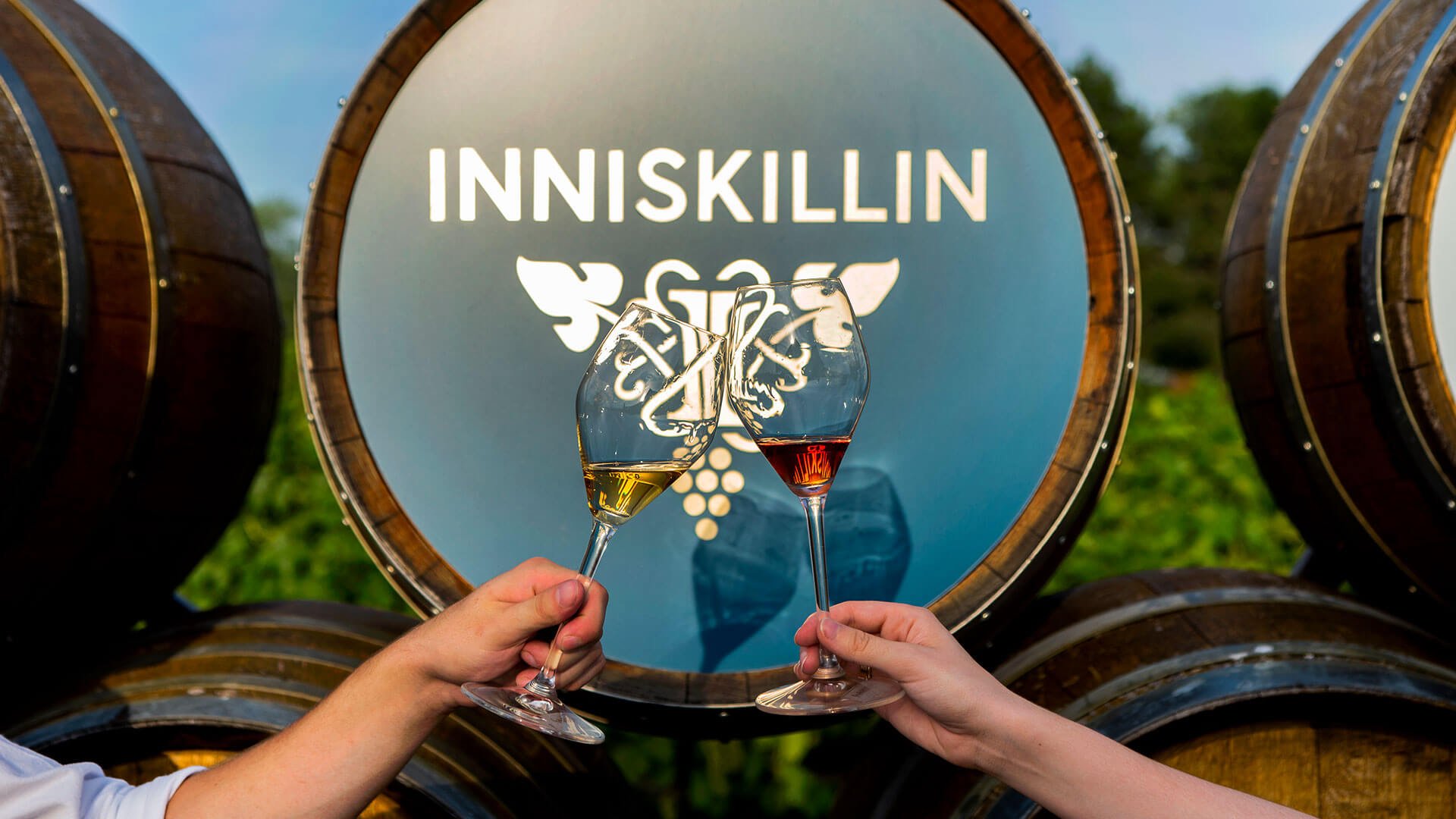 Inniskillin White and Rose Wine in front of wine barrels.