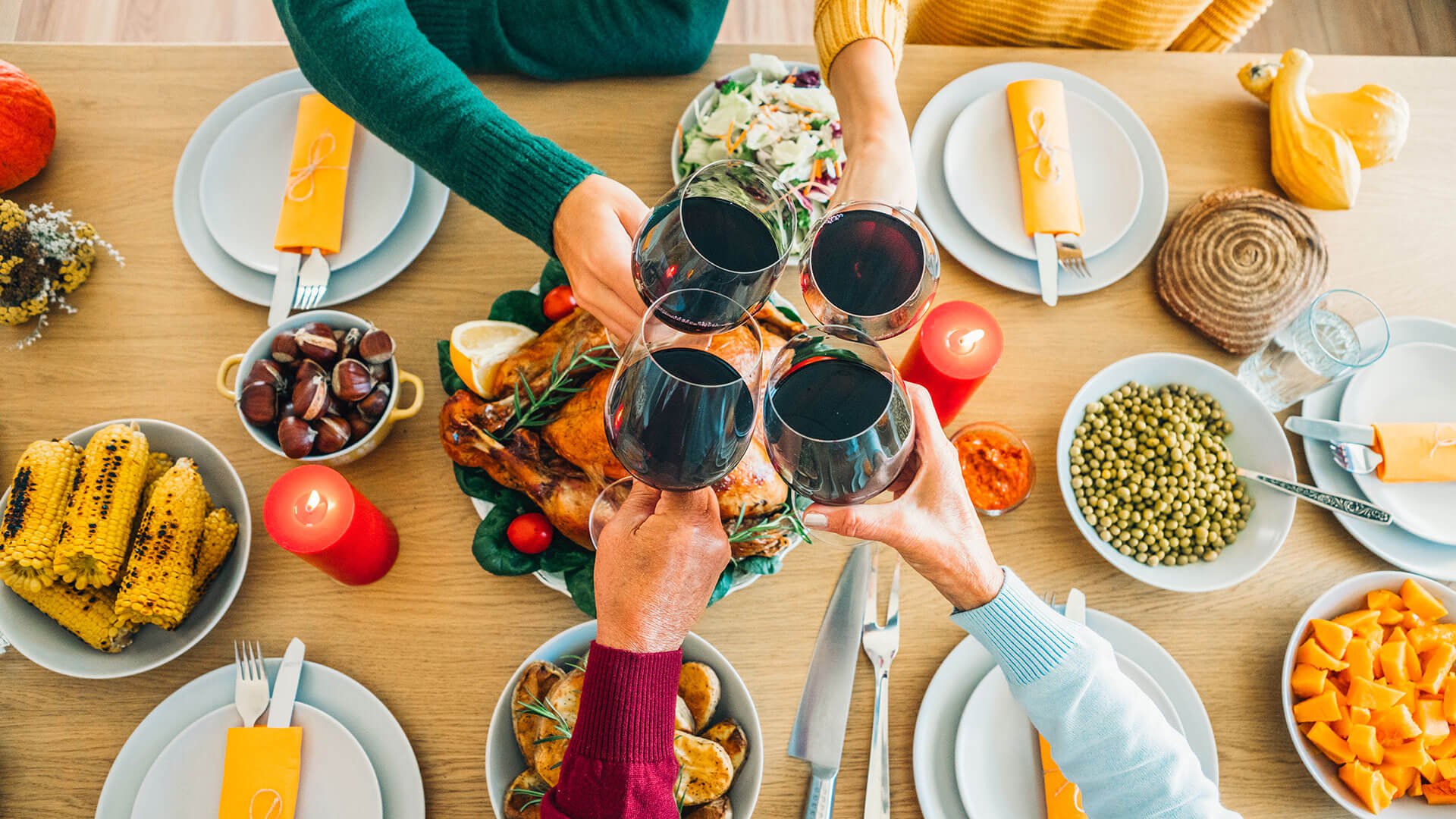 Toasting with red wine, over a dinner table of food.