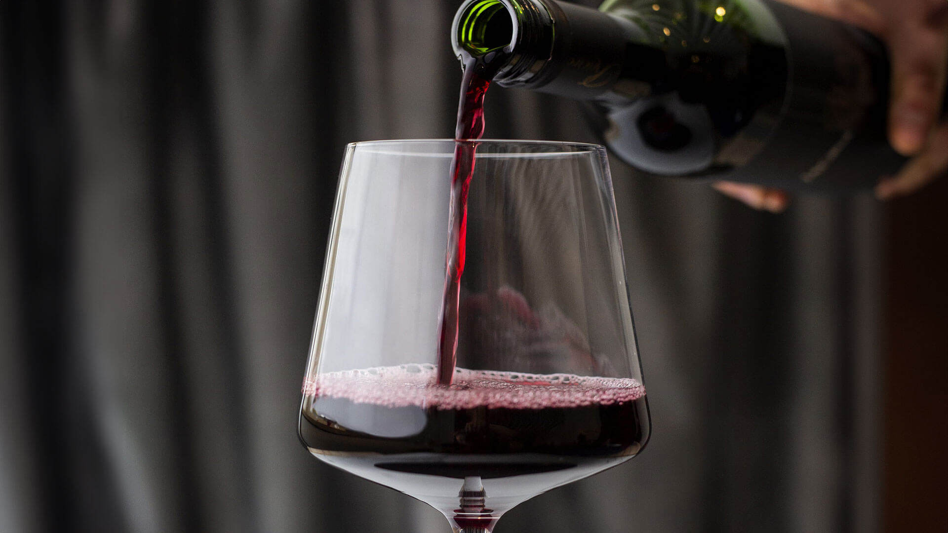 Pouring red wine into a red wine glass.