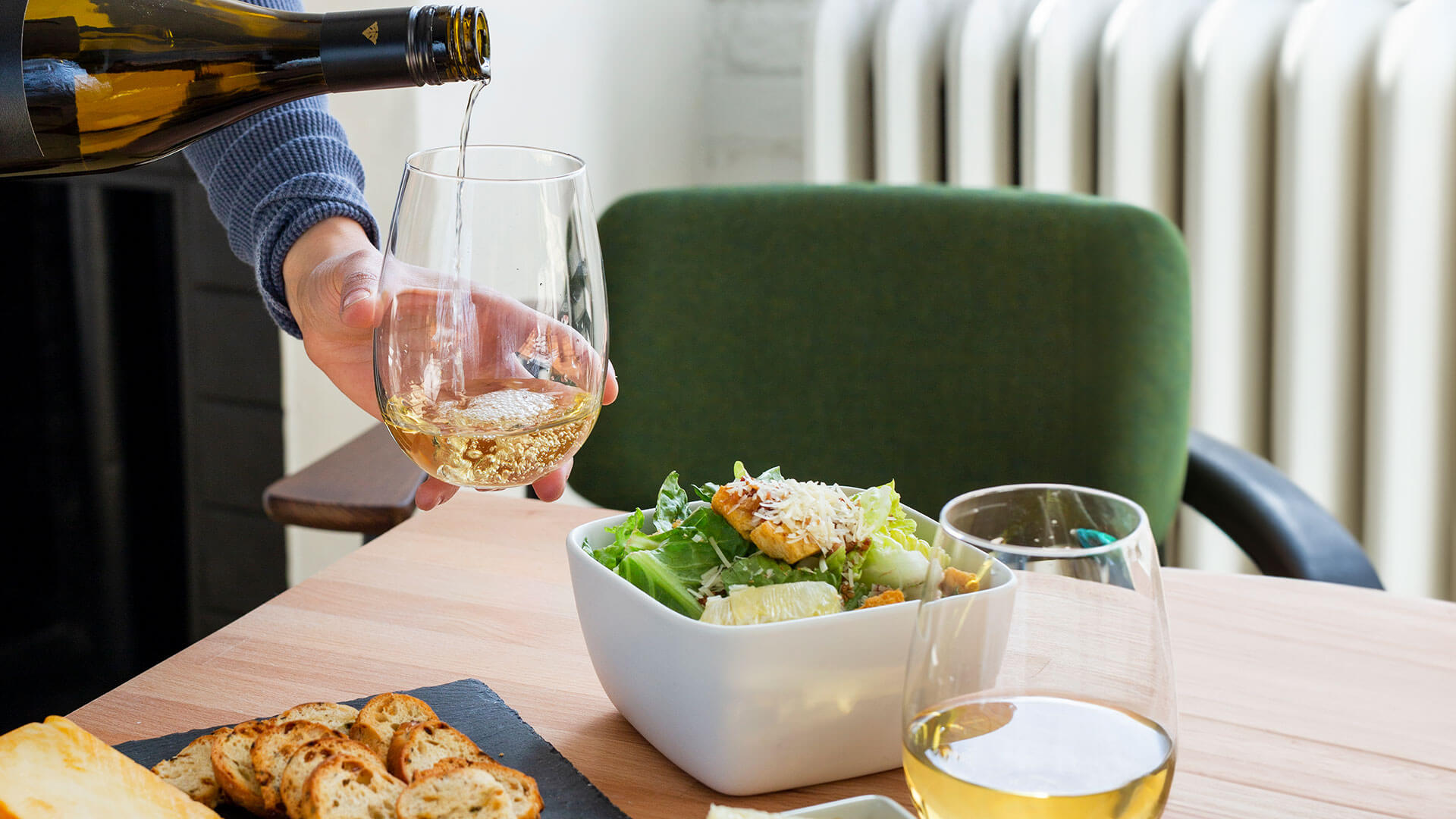 Pouring of Inniskillin Reserve Chardonnay into a glass, and paired with a salad, aged cheese and crackers.