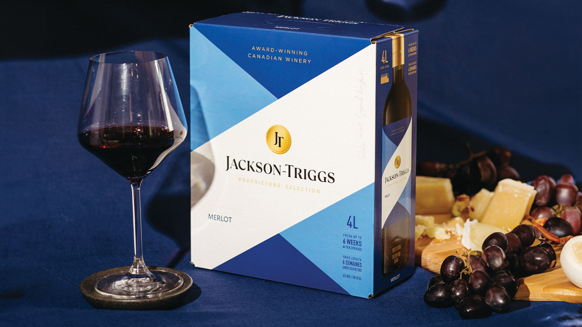 Couple of wine enthusiasts enjoying a glass from the Jackson-Triggs Merlot 4L with some cheese and grapes.  
